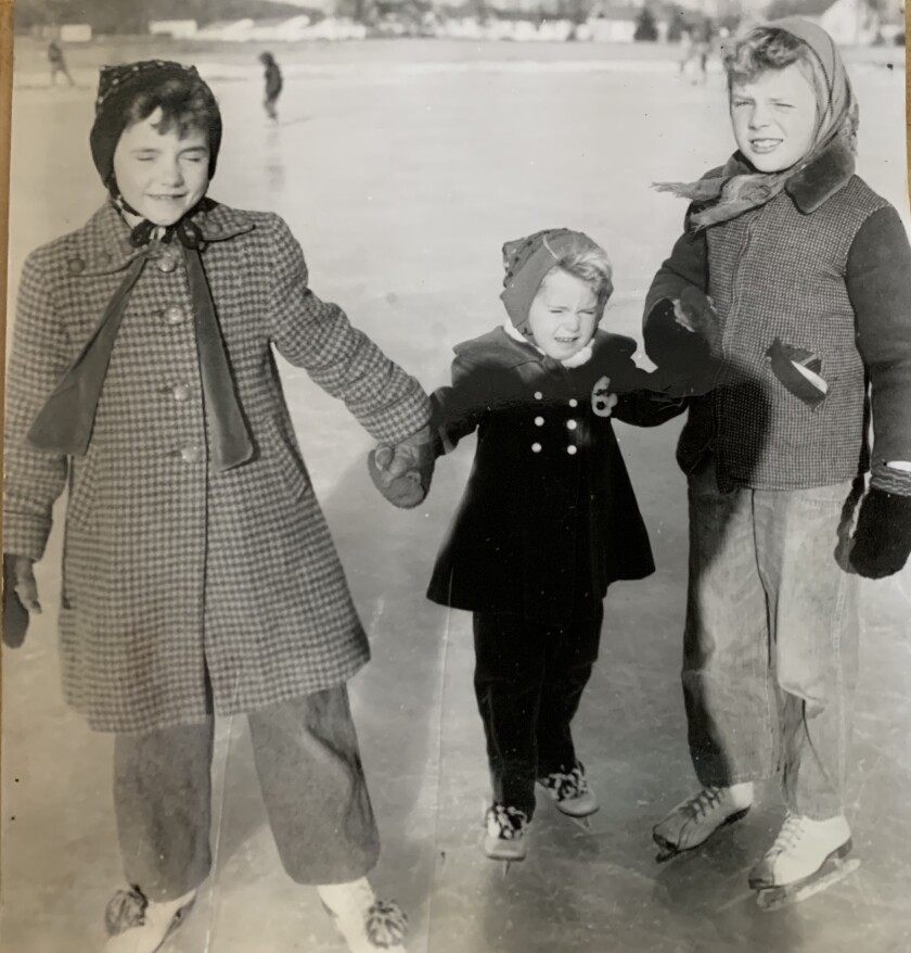 Warmly dressed children hold hands and skate on a sunny winter day.jpg