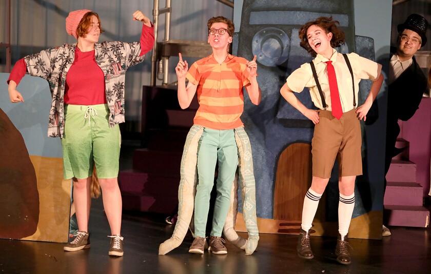 Patrick, played by Addie Poskozim, left, Squidward, played by Julian Robbins, center, and Spongebob, played by Gwen Hall, sing as the Mayor, played by Brady Hansen, right, pops his head out from behind Squidward’s house
