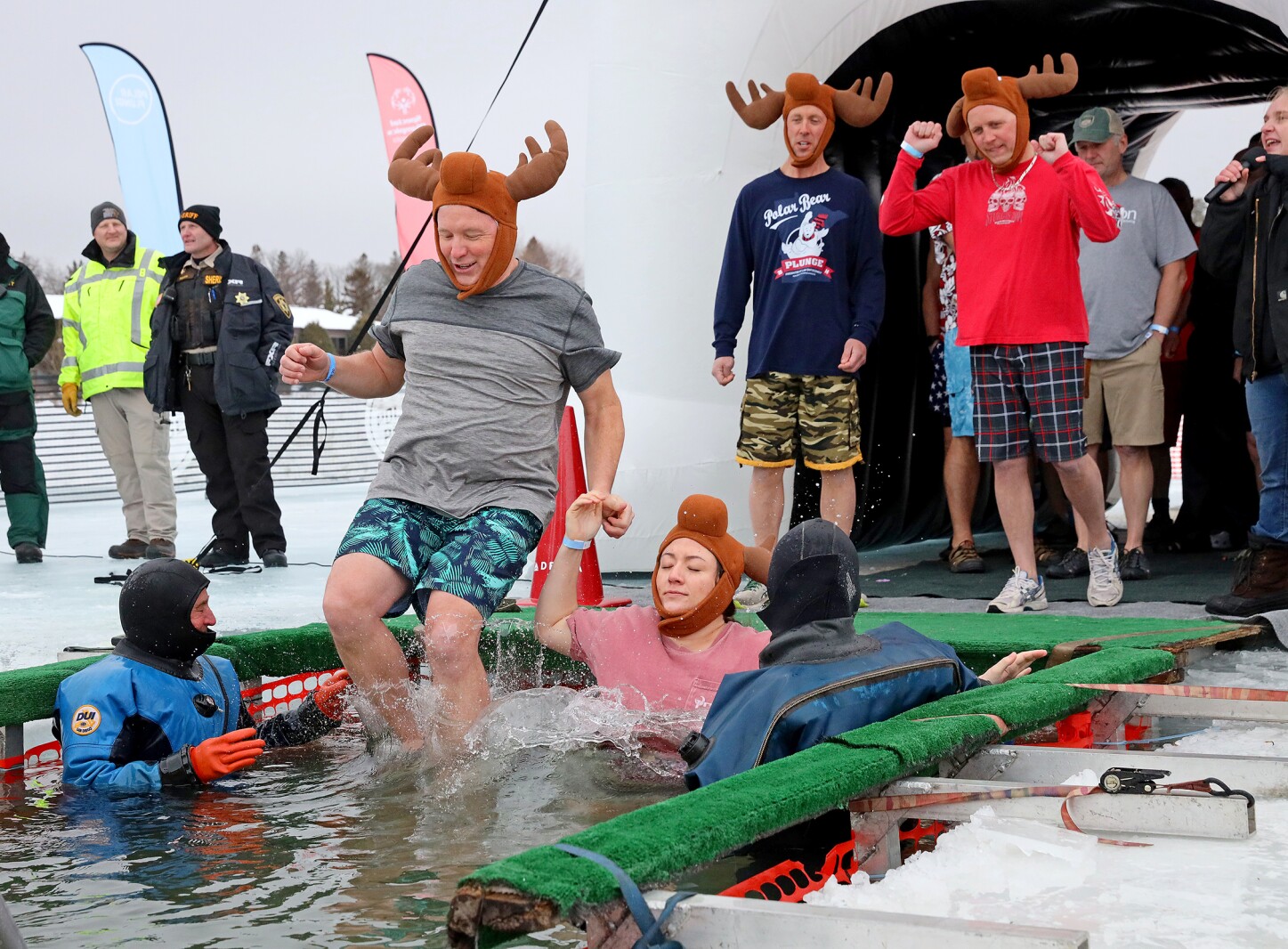 People jump into the water during the Polar Plunge event on Pelican Lake.