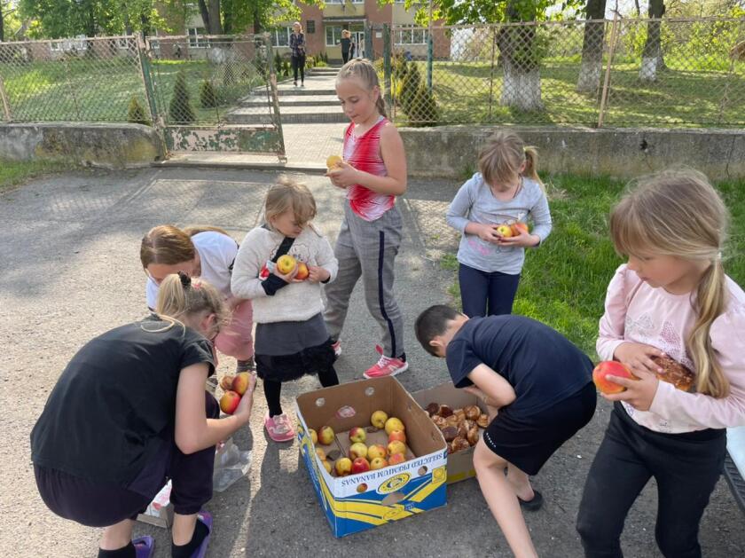 Children load their hands with bread and apples.