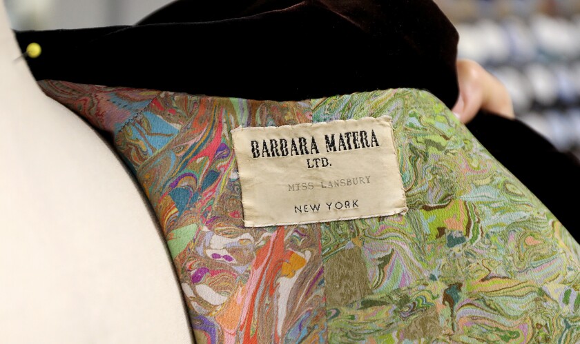 A tag on the inside of a coat reads Miss Lansbury on the costume worn by Angela Lansbury from the play Dear World
