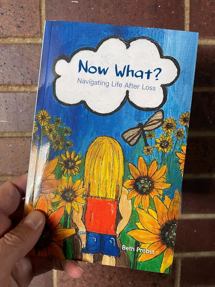 White person's hand holding book: "Now What? Navigating Life After Loss" by Beth Probst.