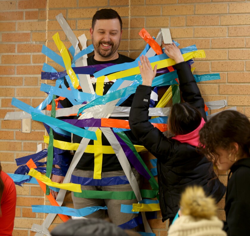 Patrick Mahoney, social studies teacher at Worthington High School, gets taped to the wall in the school's hallway as part of a United Way of Nobles County fundraiser Friday, Feb. 10, 2023, during a basketball game.