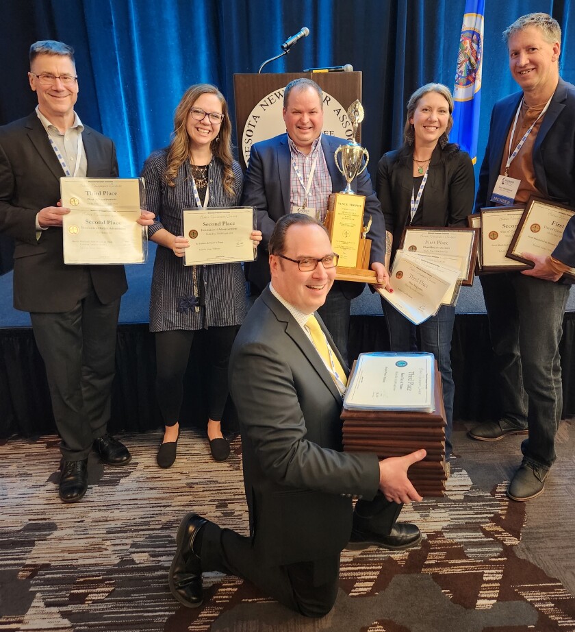 six employees holding certificates, plaques and a trophy