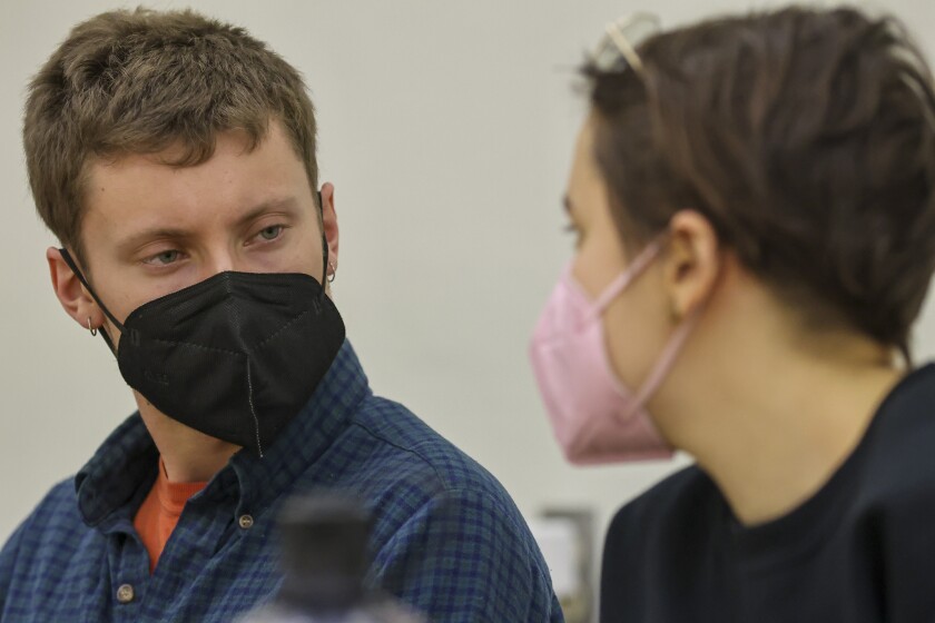 People at a meeting table with laptops and face masks