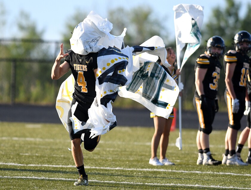 The banner was really the only thing slowing down the Tigers in the first half of Northwestern’s season opener with Ashland as quarterback Luke Sedin (4) tries to pull the paper off his helmet as he runs to mid-field