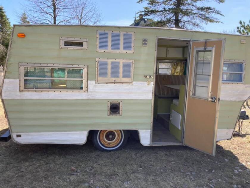 An old camper is covered in seafoam paint.
