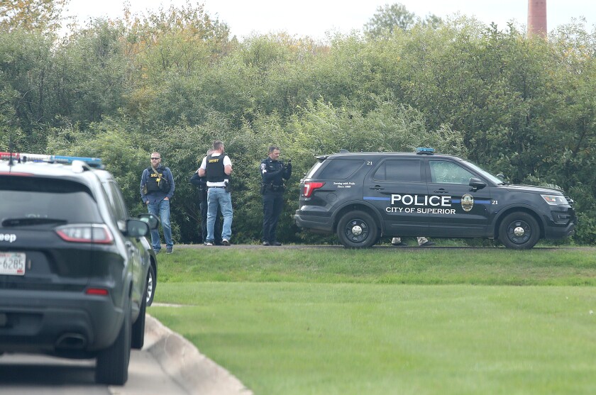Senior law enforcement officers meet on a side road near the corner of Raspberry Avenue and Vogel Street
