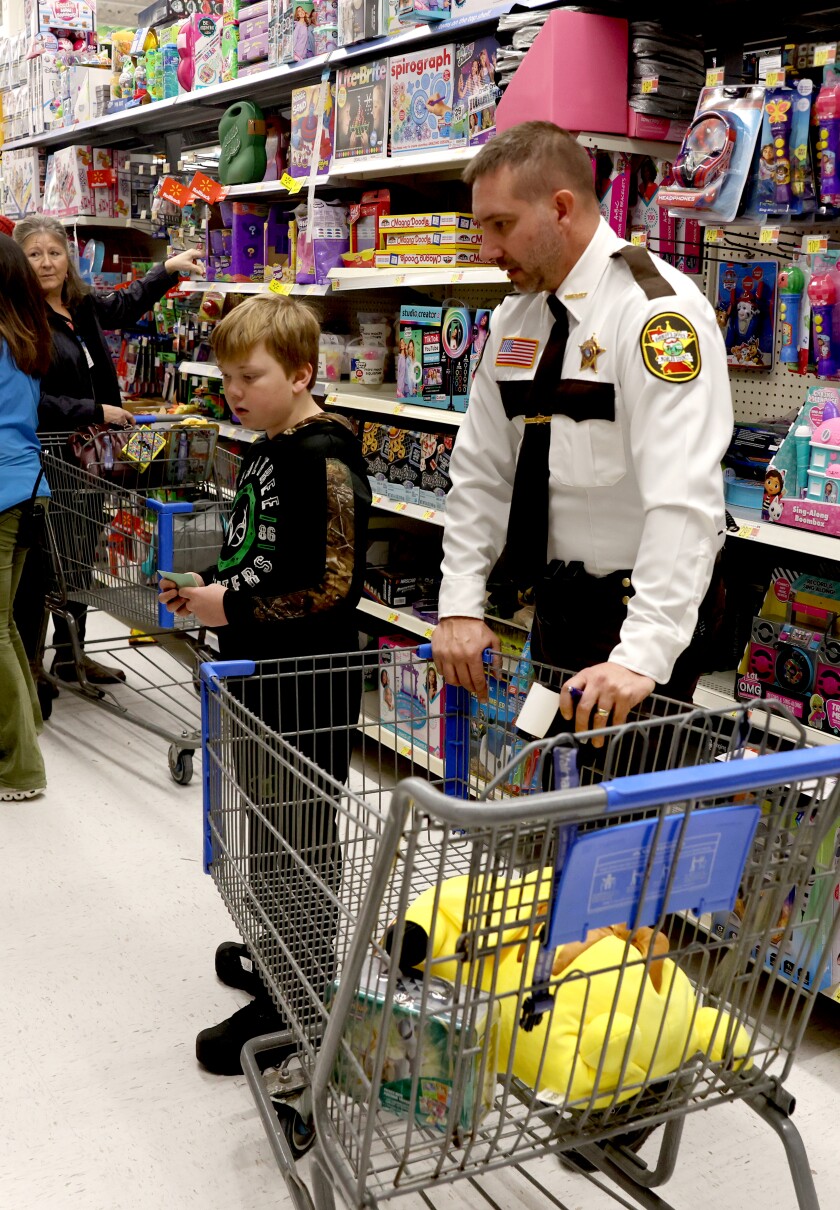 Nobles County Sheriff Ryan Kruger helps a young gentleman with his shopping list in the toy aisle at Walmart during the annual Shop With a Cop event Tuesday evening.