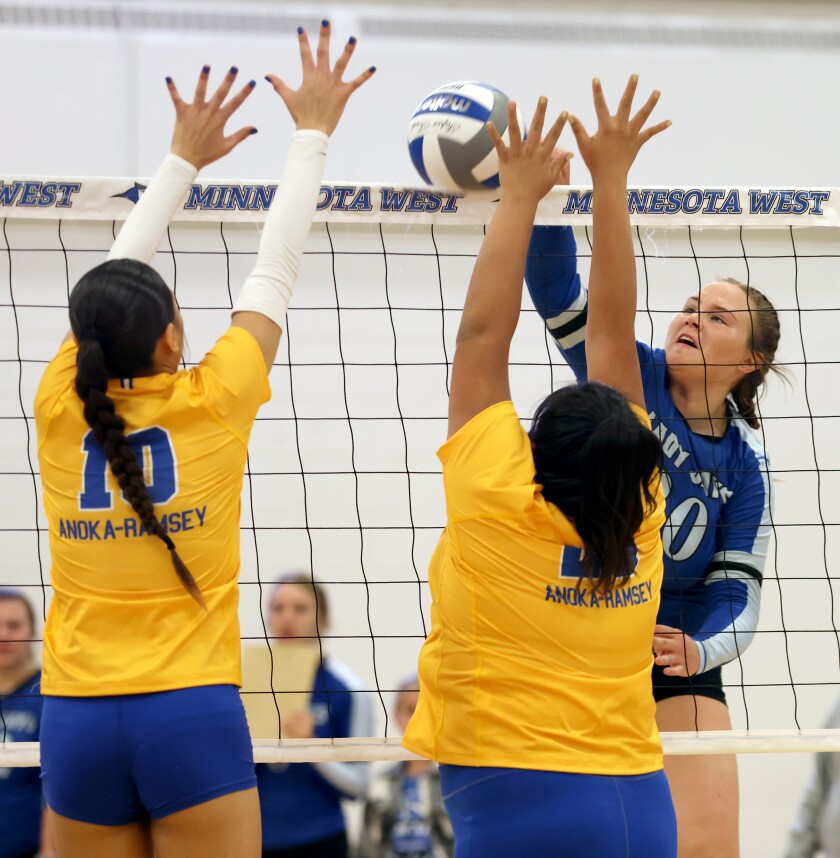 Minnesota West Lady Jays Kennedy Buckneberg spikes the ball between Anoka-Ramsey Golden Rams defenders Aniah Smith (10) and Alexis Crow during a Saturday noon match.