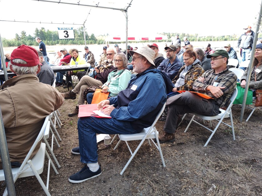 People sit in chairs during an outdoor classroom session.