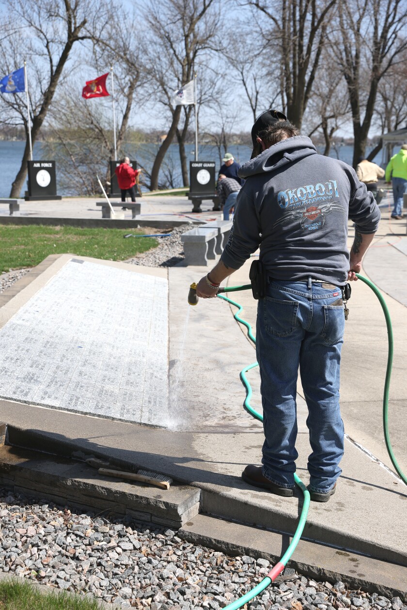 Bryon Clark sprays down pavers with the names of Nobles county veterans at the Freedom Veterans Memorial Park during VFW service day Saturday morning.