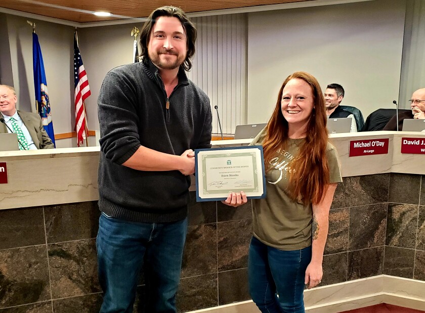 Two people shake hands and exchange a certificate