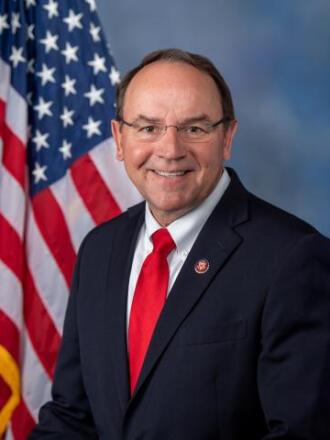 Man in suit in front of U.S. flag