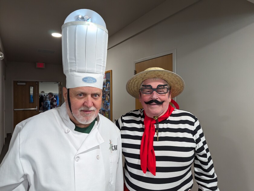 Two men pose for a photo, on in a chef outfit and one dressed like a Venice gondolier