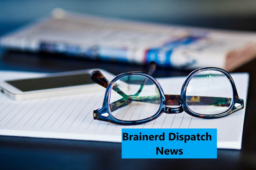 Dispatch brief logo with glasses sit on a pad of paper with newspaper and cellphone in the background