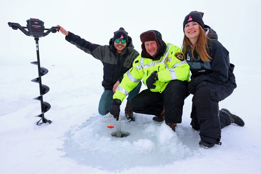 A trio poses by the hole in the ice.