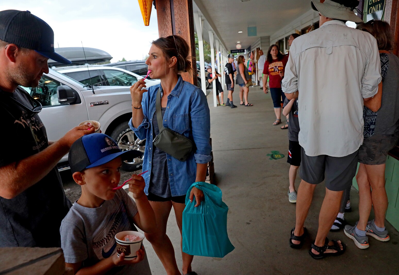People eat ice cream on the covered walkway to avoid the rain Wednesday, Aug. 24, 2022, outside of The Chocolate Ox in Nisswa.