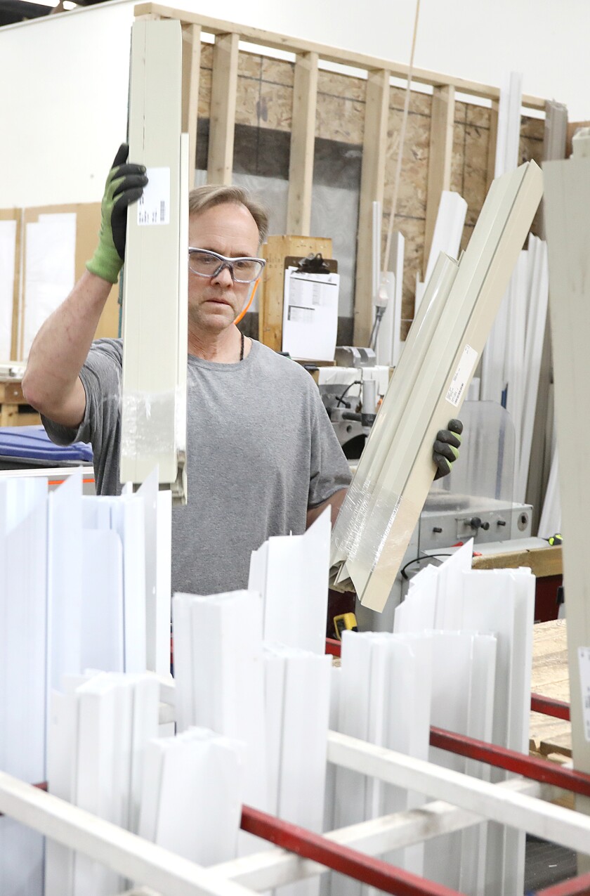 Tony Drewes places cut and wrapped frames in the correct bins at Fentech in Superior