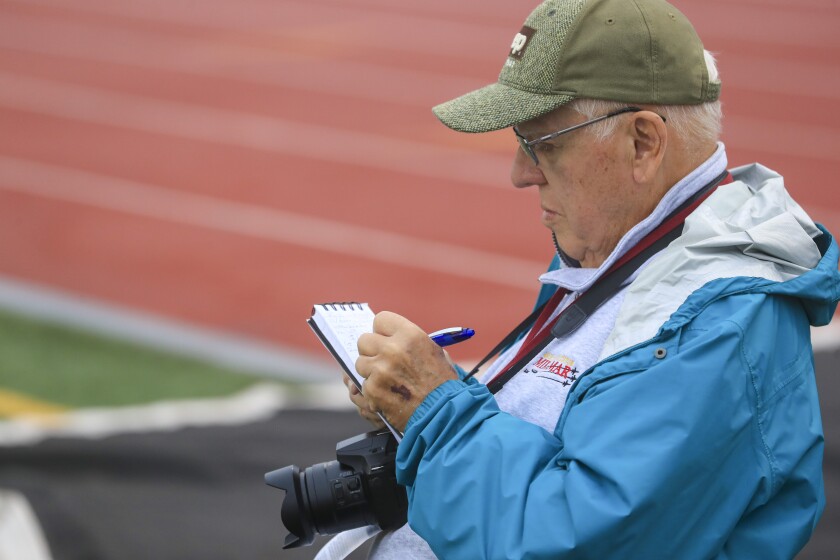 man writing notes on a pad of paper