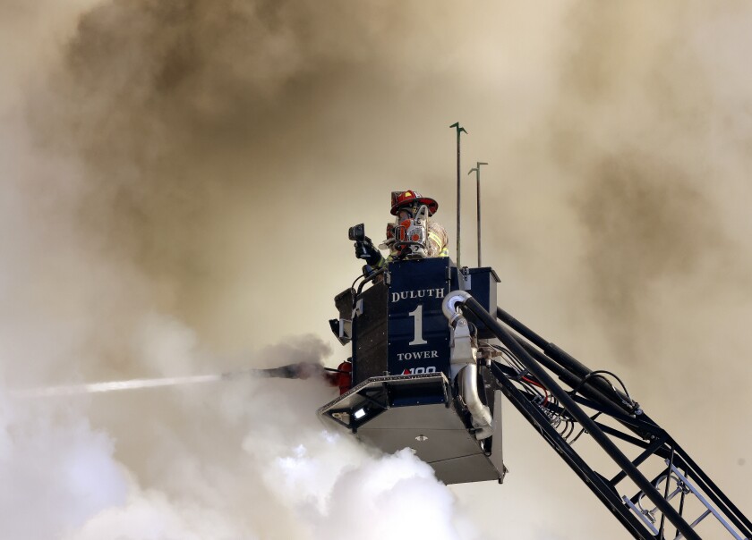 Firefighters on Tower 1 battle the blaze at the Esmond Building Monday, Jan. 10, 2022, against a backdrop of smoke.
