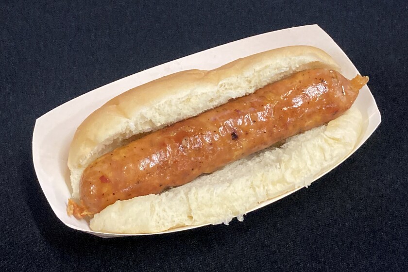 An Italian chicken sausage inside of a bun served in a paper tray.
