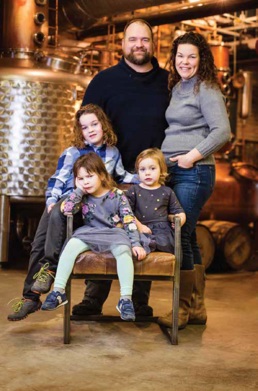 A family of five poses in a distillery.