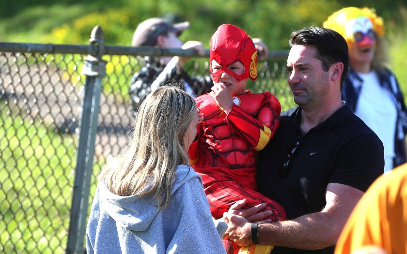 Kid wearing a Flash costume being held by his father