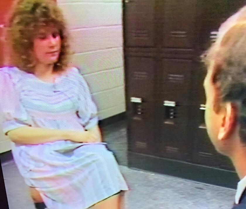 A woman with curly brown hair sits for an interview.