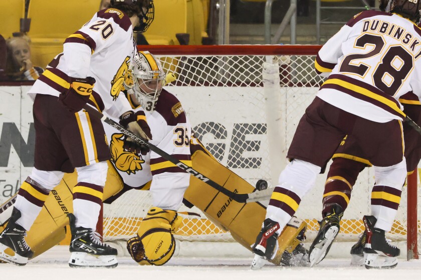 A college hockey player plays in an indoor rink