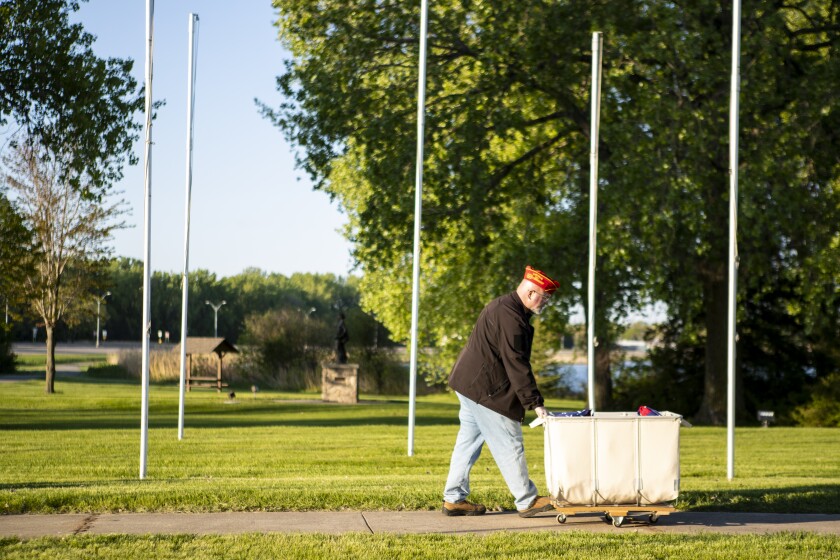 Marine veteran John Larson rolls a container of folded American flags out to the Flags of Honor Memorial as workers put up 100 American flags in observance of Memorial Day on Friday, May 27, 2022