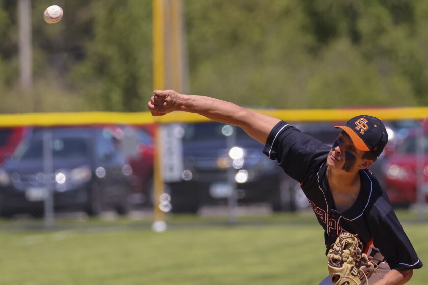 High school boys in black and orange uniforms with white shorts play baseball