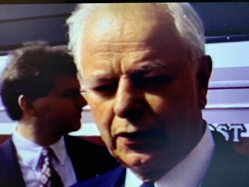 A close-up of a white-haired man in a suit.