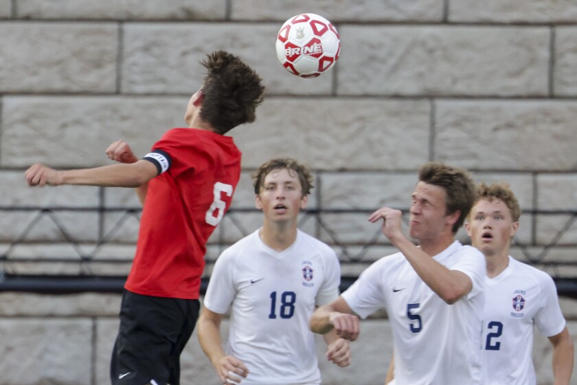 High school boys soccer players in red uniforms playing players in white uniforms outdoors