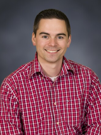 A man smiling in plaid.