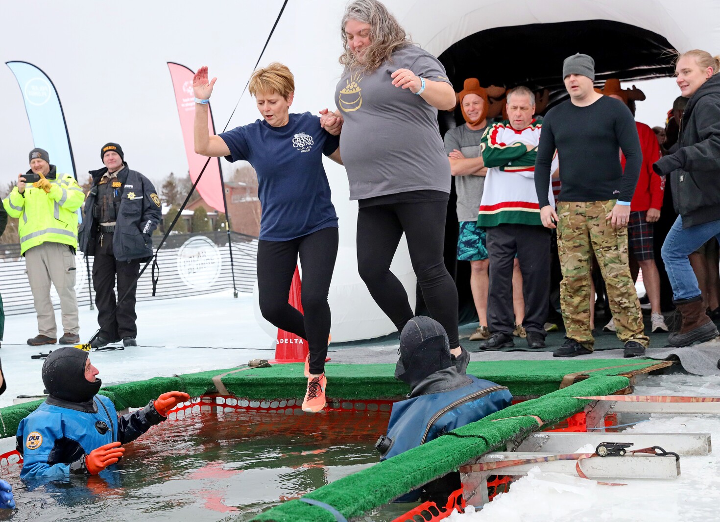 People jump into the water during the Polar Plunge event on Pelican Lake.