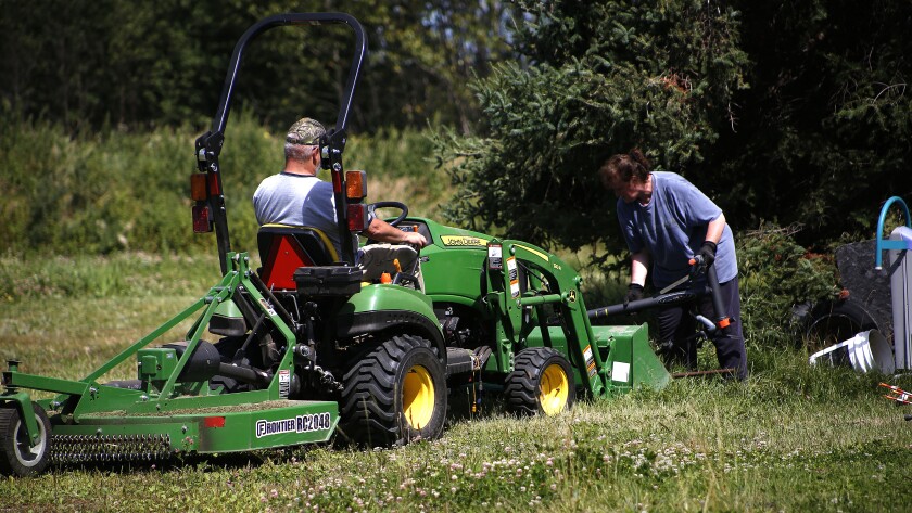 Woman loads junk on a tractor driven by a man.