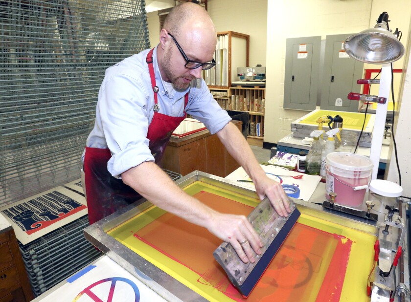 T01.05.2019 -- Steve Kuchera -- 01xx19.N.DNT.MLKposterC1 -- Darren Houser of Antimonii Studios screen prints a “The Current Crisis” poster, themed for this year’s Martin Luther King Jr. Day events. The title comes from “The Current Crisis in Race Relations,” an article King Jr. wrote in 1958. The Duluth branch of the NAACP is selling three different designs of posters, one of which is drying behind Houser. Steve Kuchera / skuchera@duluthnews.com