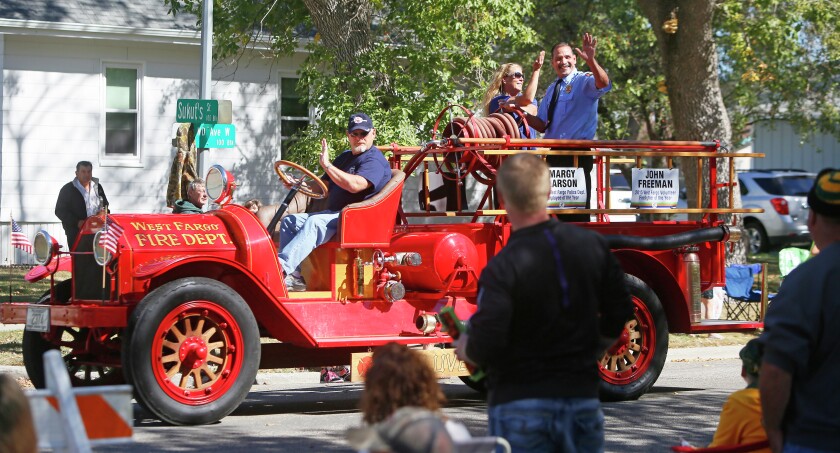 Retired West Fargo Fire Department Chief Roy Schatschneider drives city employees of the year Margy Larson and John Freeman during the West Fest Parade Saturday, Sept. 19, 2015.David Samson / The Forum
