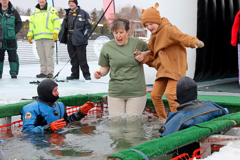 People jump into the water during the Polar Plunge event on Pelican Lake.