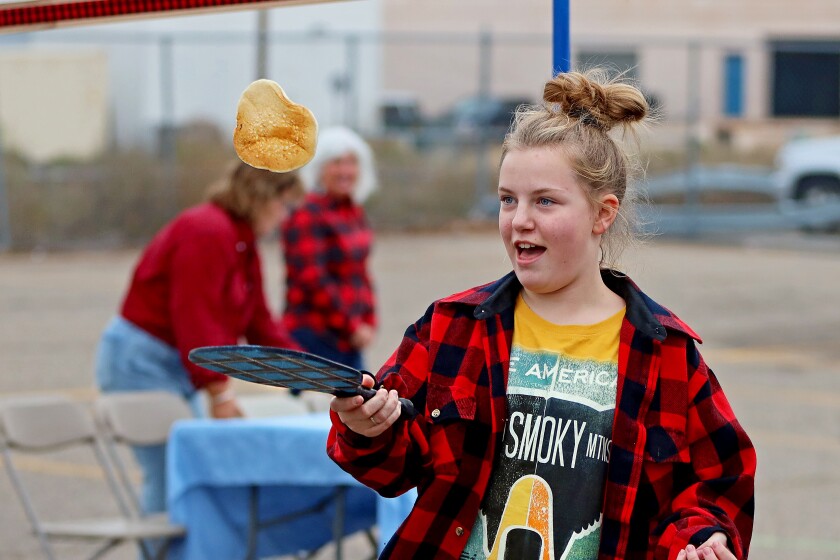 A girl flips a flapjack with a paddle.
