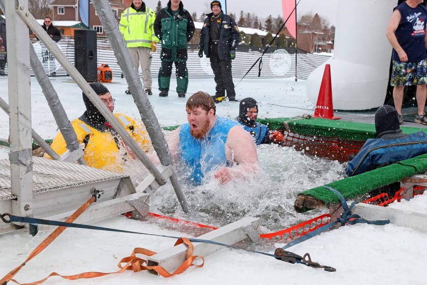 People jump into the water during the Polar Plunge event on Pelican Lake.
