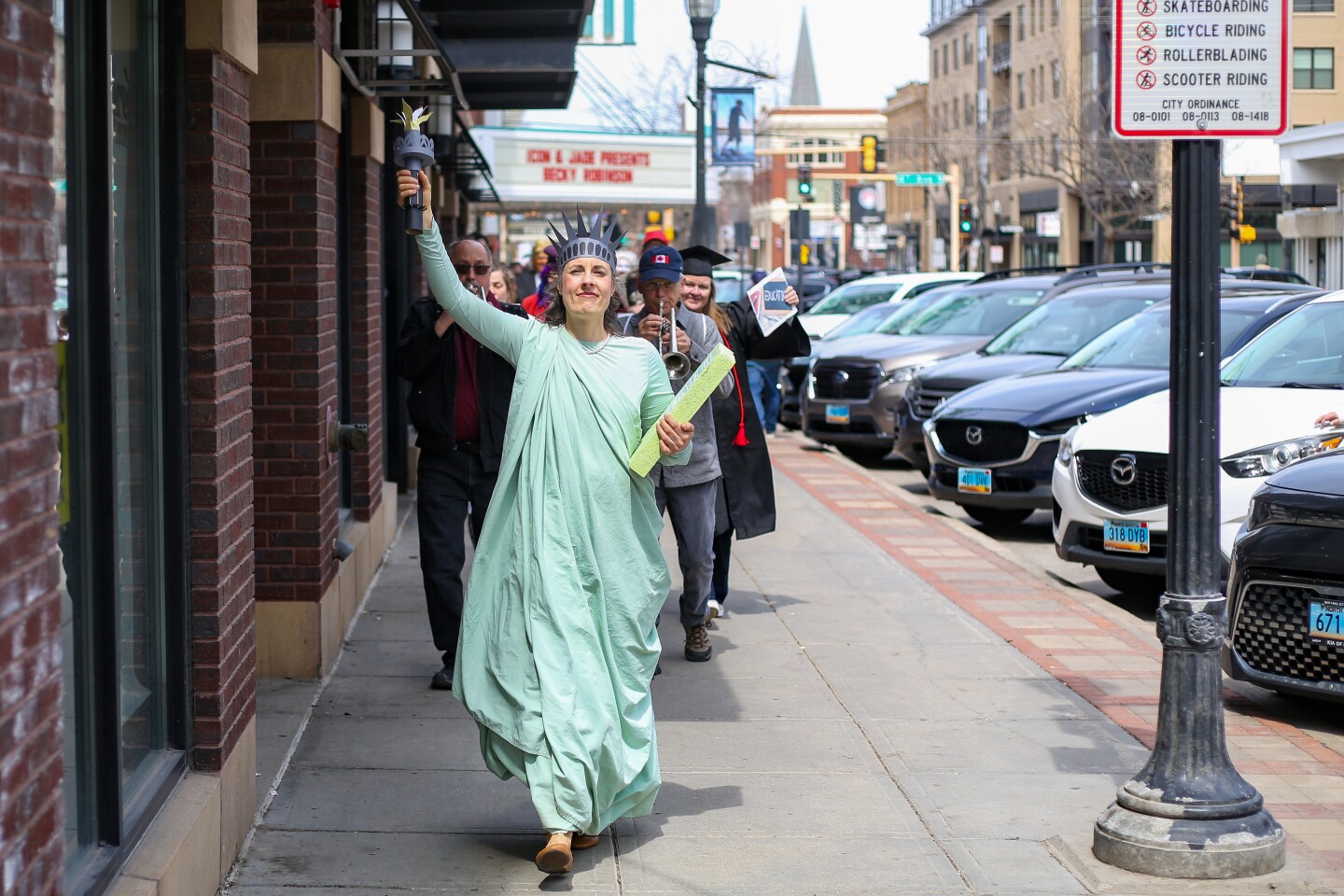 Bethany Dixon leads more than 200 protesters through downtown Fargo dressed as "Liberty" in a street theater protest called "Let Them Eat Cake" on Saturday, April 26, 2025.