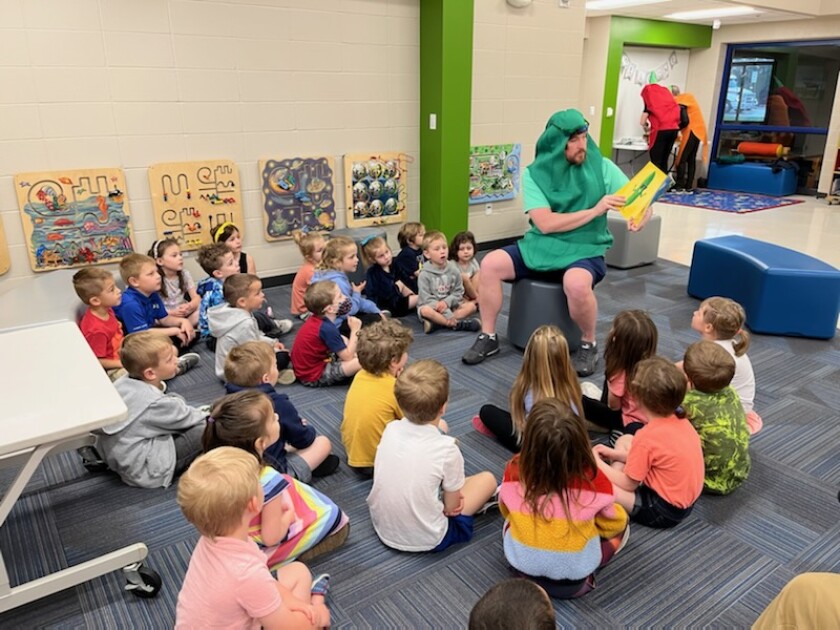 Brainerd Mayor Dave Badeaux wears a cucumber costume and reads to children