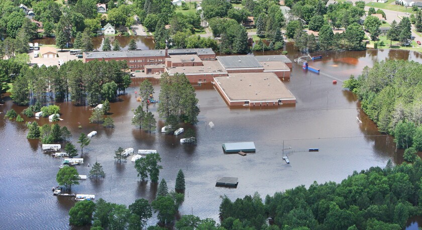 A school and surrounding homes are surrounded by flood waters in an aerial photo