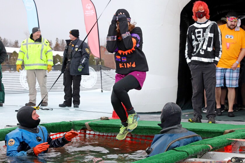 People jump into the water during the Polar Plunge event on Pelican Lake.