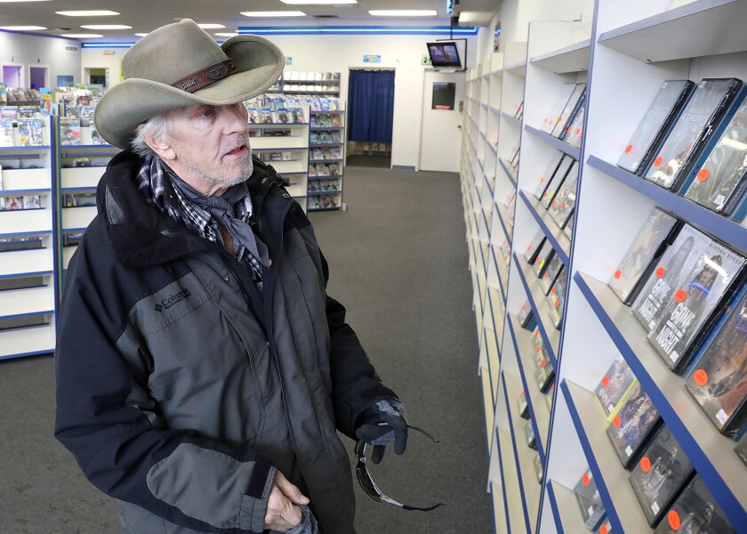 Tim Nelson looks over the shelves for a DVD to rent at Video Vision in Superior