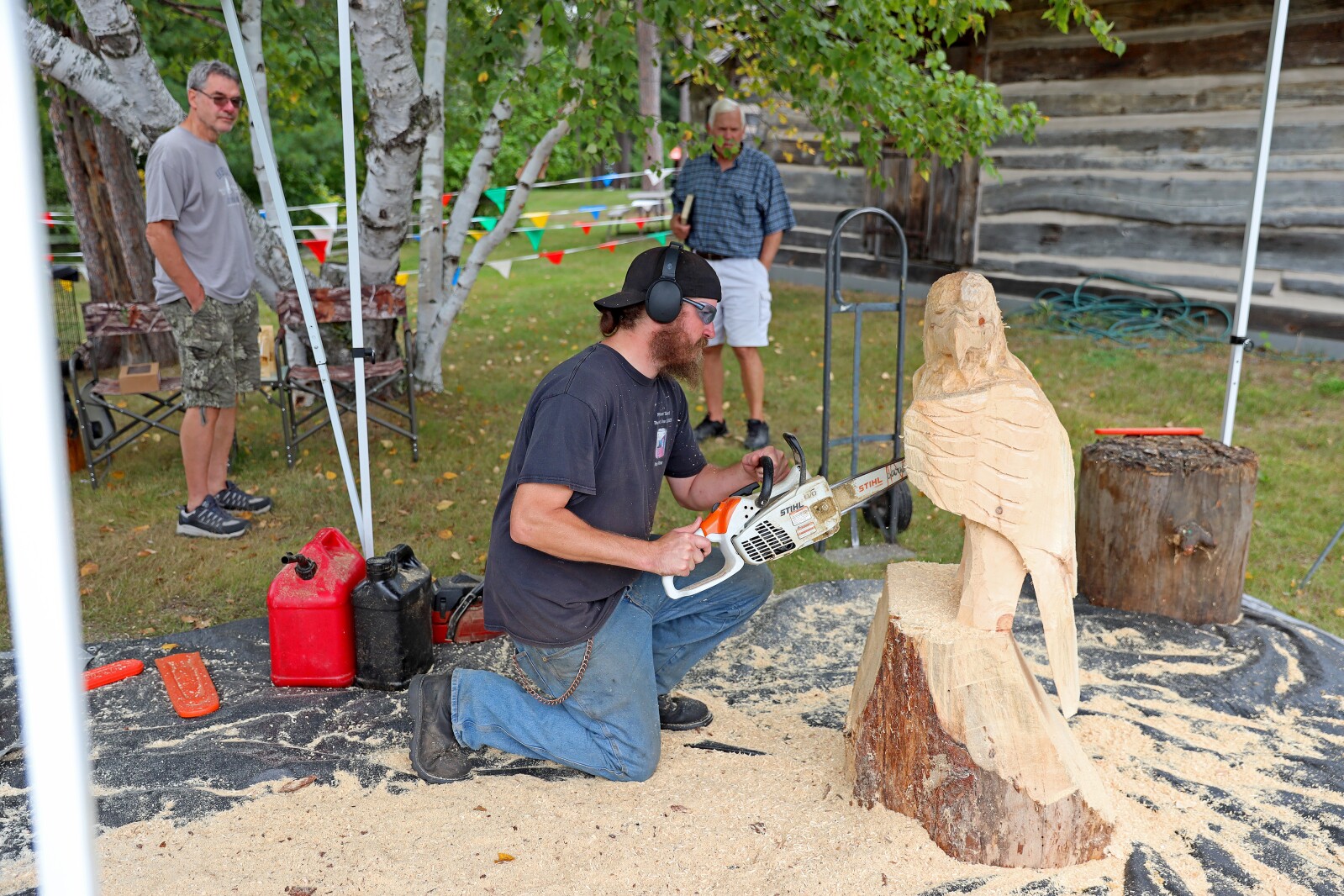 A chain saw artist carves an eagle into a log.