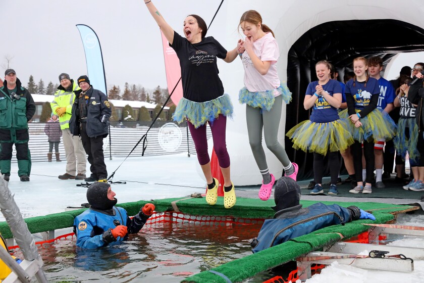 People jump into the water during the Polar Plunge event on Pelican Lake.