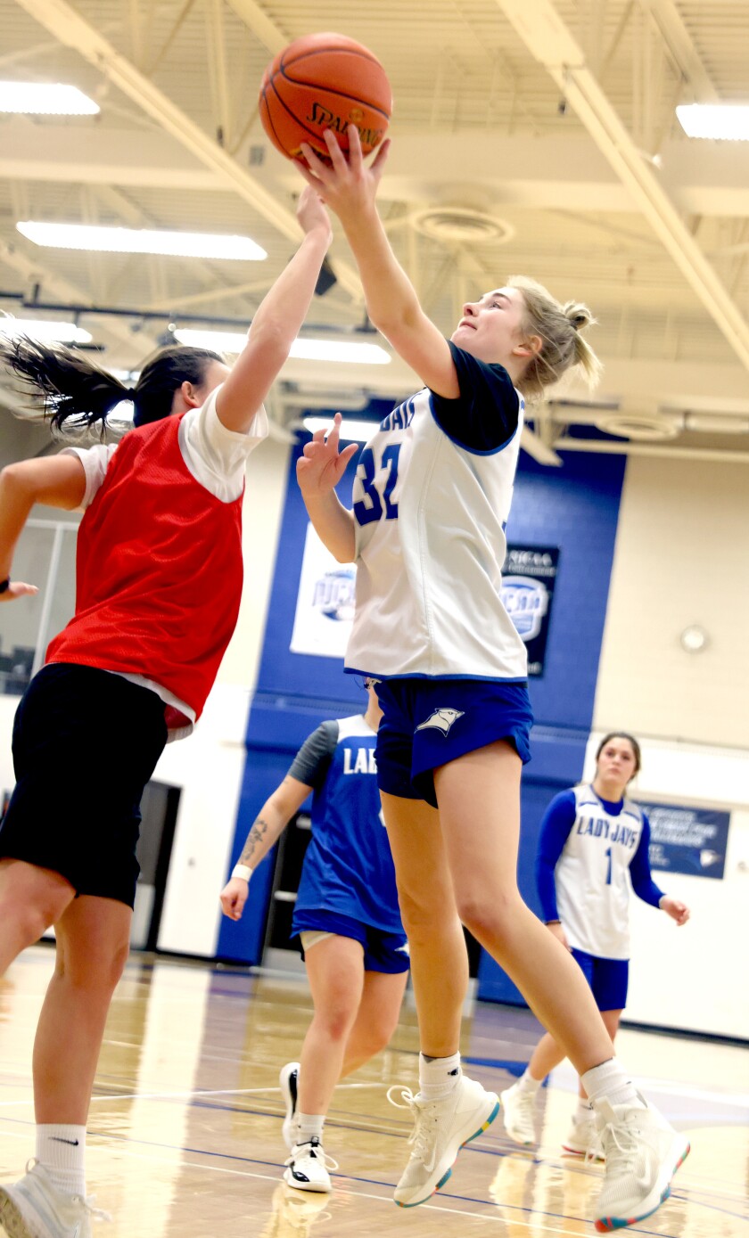 Minnesota West women's basketball player Tia Murray leaps past assistant coach Avery Van Rockel as she makes a shot during practice.